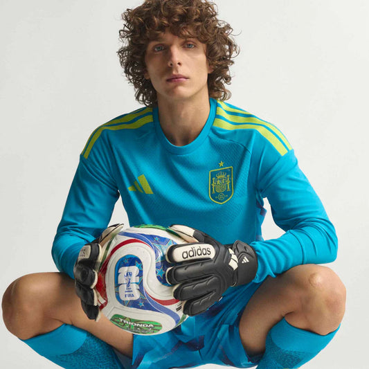 Modelo sentado con el balón vistiendo la equipación de portero de la Selección Española. Consigue tu elástica azul de manga larga con la mejor oferta online.